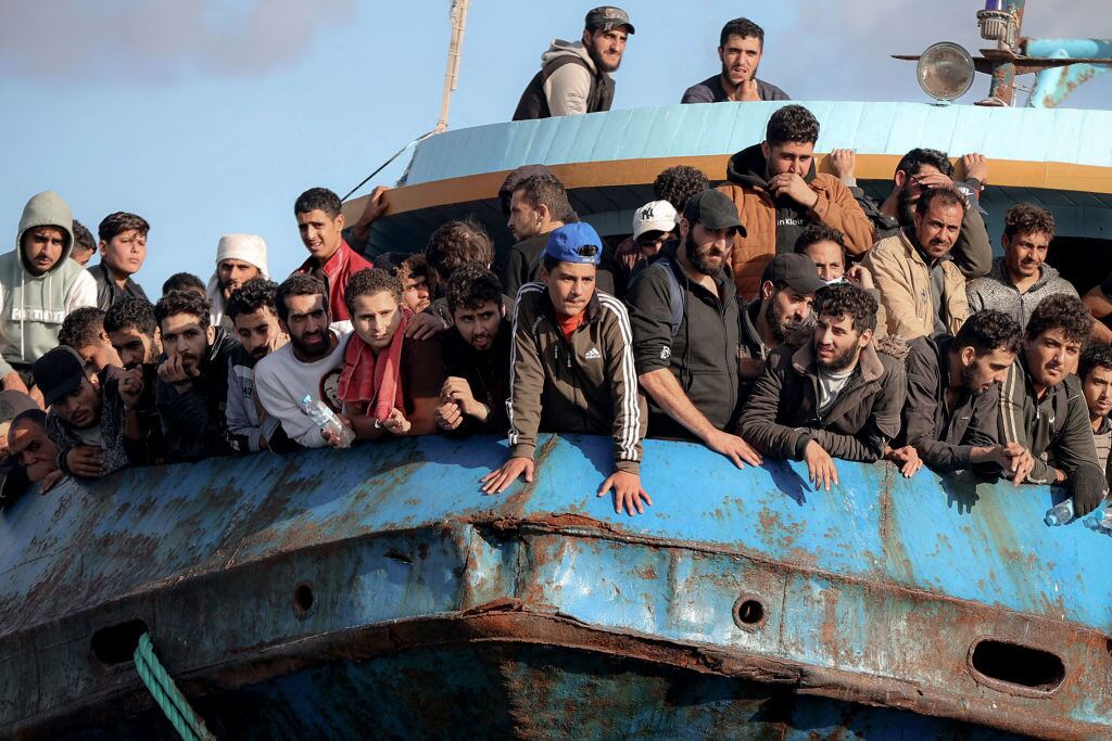 TOPSHOT - Rescued refugees and migrants stand aboard a boat at the town of Paleochora, southwestern Crete island on November 22, 2022, following a rescue operation. (Photo by Costas METAXAKIS / AFP) (Photo by COSTAS METAXAKIS/AFP via Getty Images)