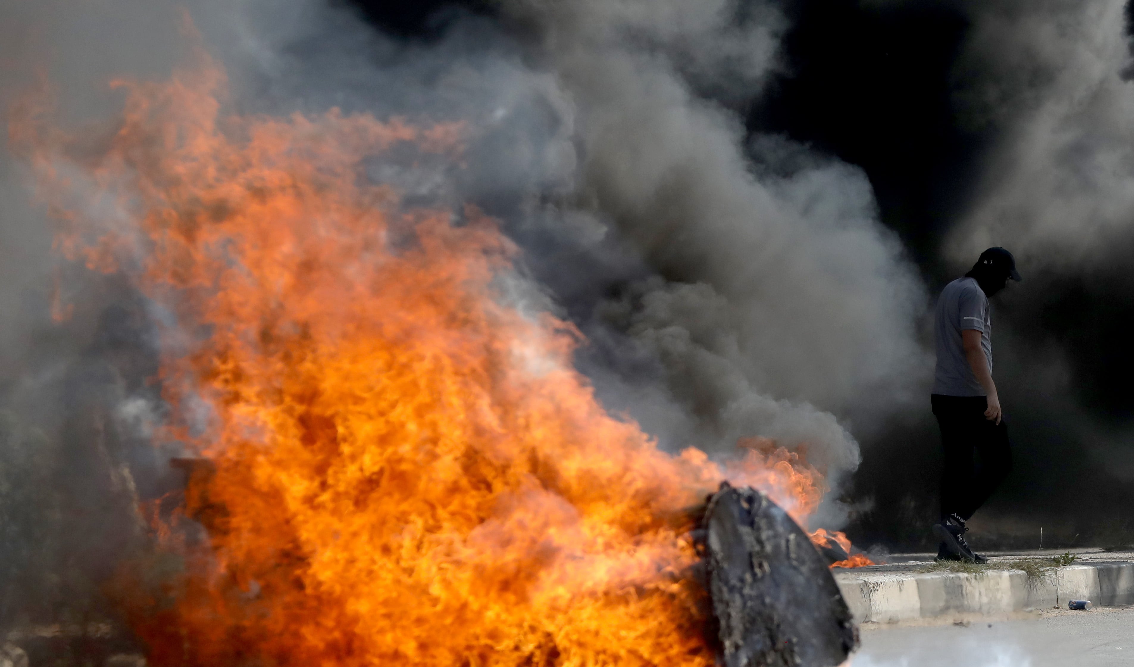 Un palestino busca refugio durante los enfrentamientos con las fuerzas israelíes en la ciudad de Naplusa, en Cisjordania, el 13 de octubre de 2023. EFE/ALAA BADARNEH