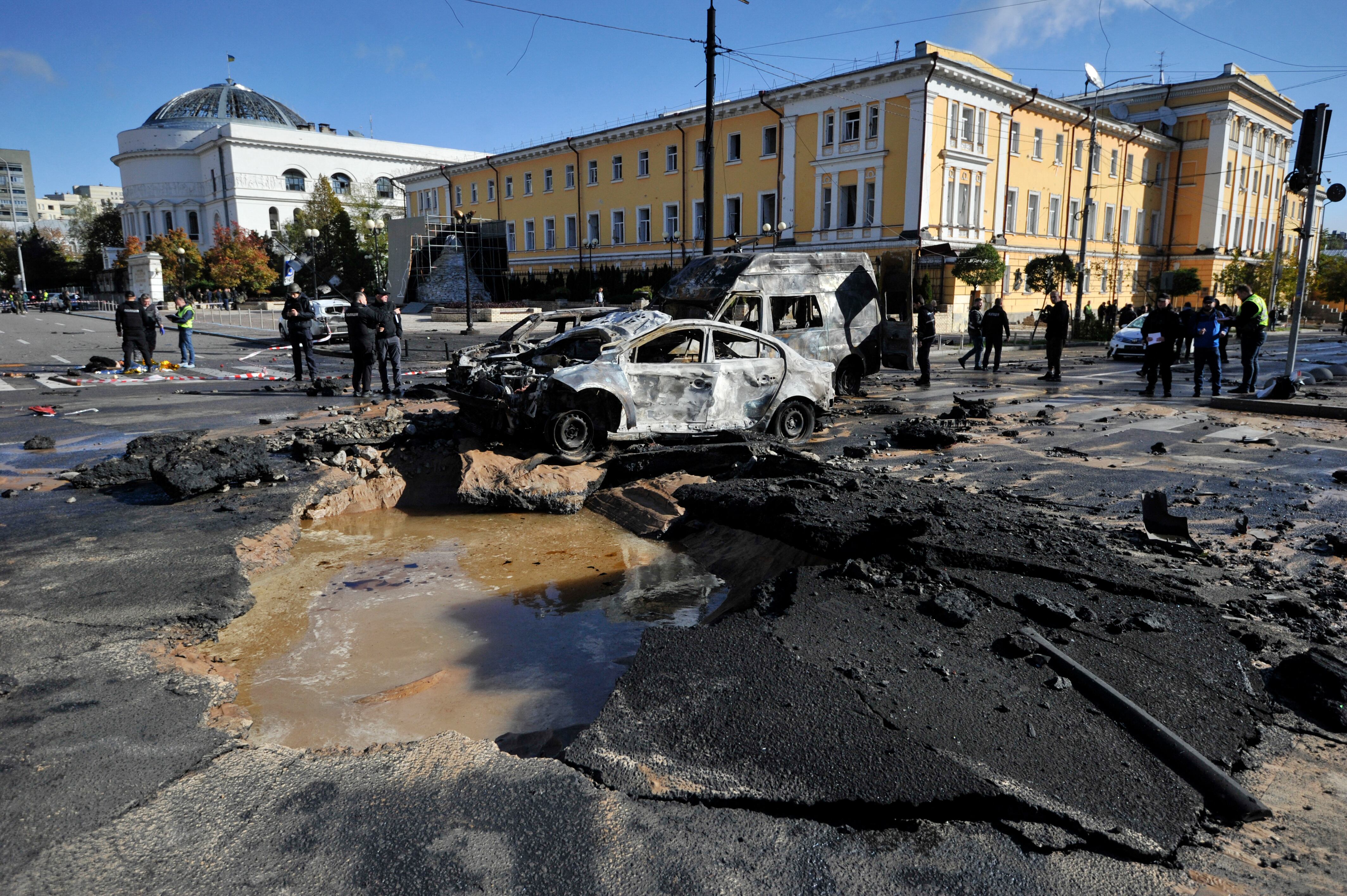 Expertos policiales examinan autos destruidos en el centro de la capital ucraniana de Kyiv después de varios ataques rusos el 10 de octubre de 2022 / AFP