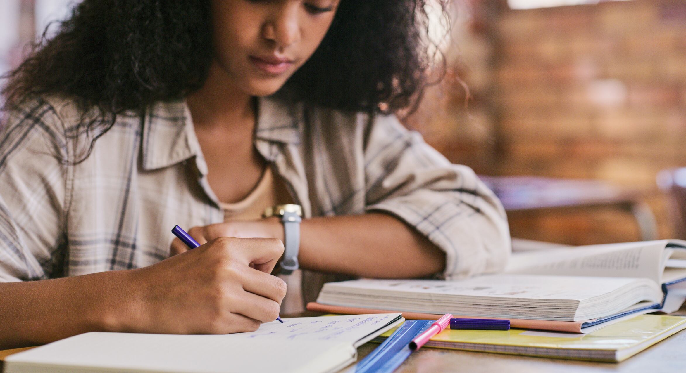 Mujer escribiendo algo en su cuaderno mientras estudia (Getty Images)