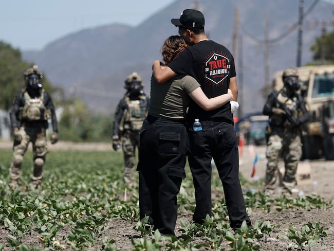 CAMARILLO, CALIFORNIA - JULY 10: People embrace near federal agents blocking a road during an ICE immigration raid (Photo by MARIO TAMA / GETTY IMAGES NORTH AMERICA / Getty Images via AFP)