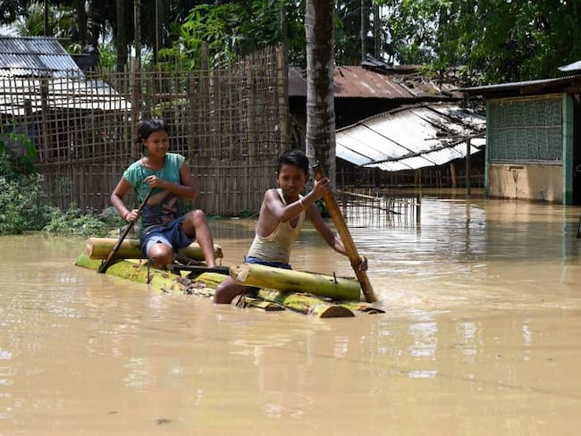 Niños utilizan una canoa de bambú para movilizarse tras las inundaciones en India.          Foto: Getty 