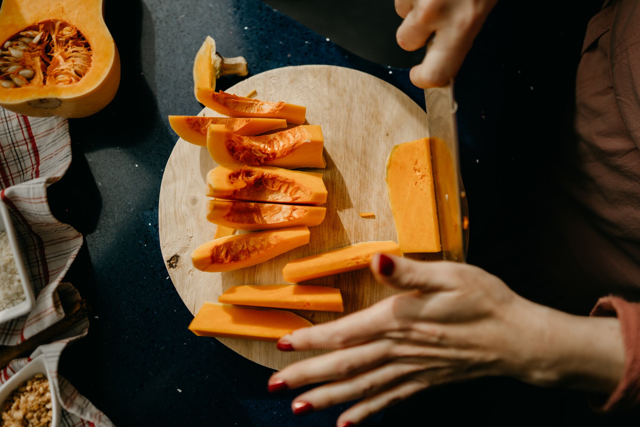 Mujer picando verduras sobre una tabla de madera (Getty Images)