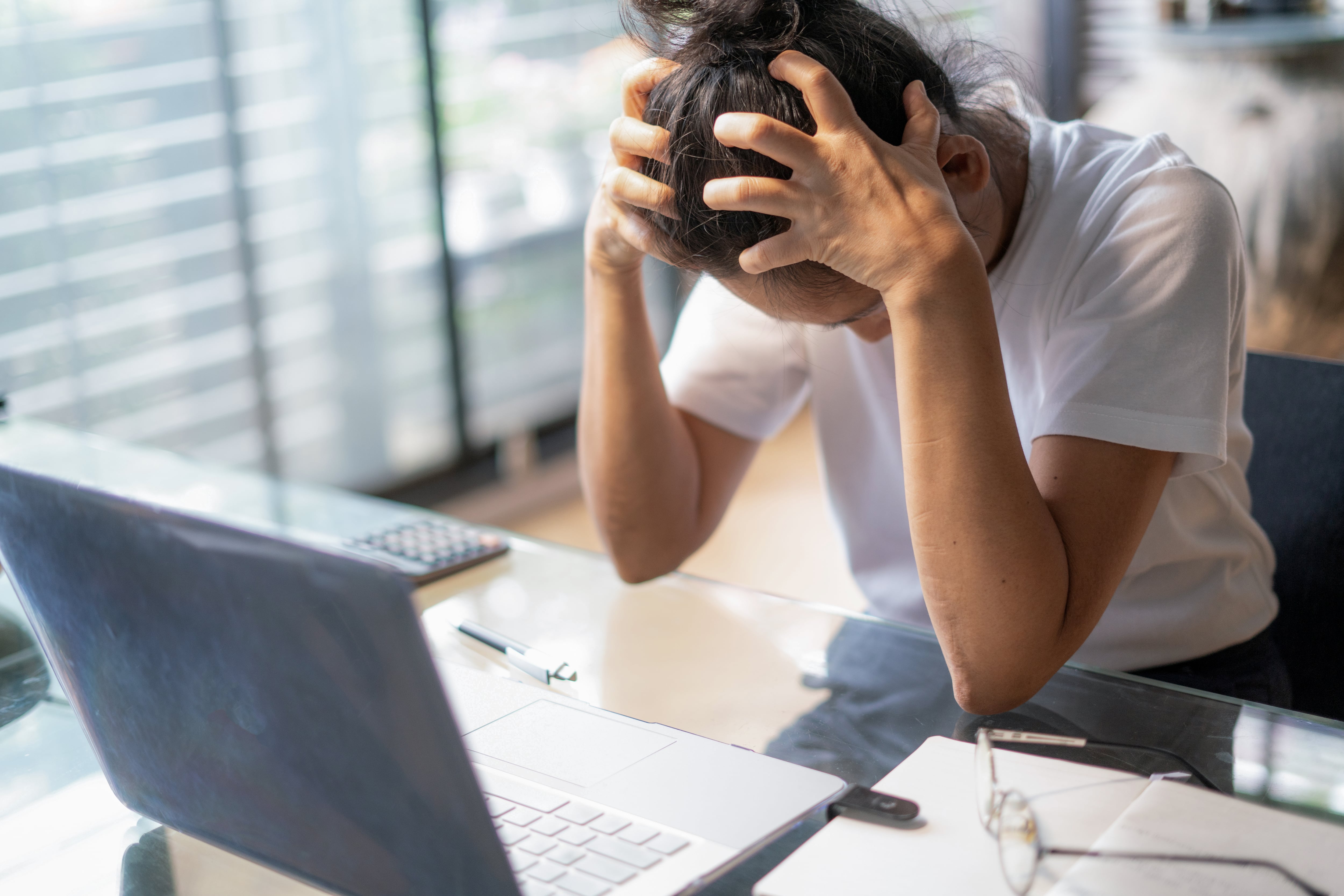 Joven cansada, con dolor de cabeza, usando un portátil en su oficina en casa. Foto Getty Images