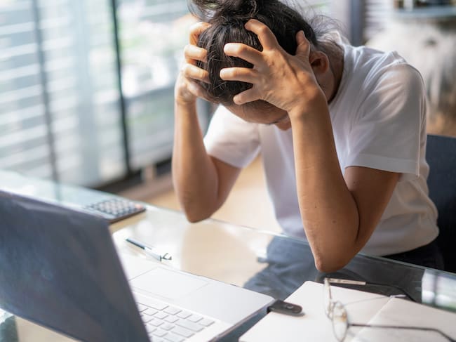 Joven cansada, con dolor de cabeza, usando un portátil en su oficina en casa. Foto Getty Images
