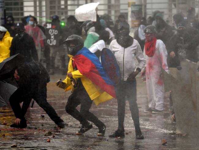 BOGOTA, COLOMBIA - APRIL 28: Demonstrators clash with riot police during a demonstration commemorating last year's national strike on April 28, 2022 in Bogota, Colombia. Social organizations have called for a demonstrations throughout Colombia to commemorate anti-government protests that surged a year ago. (Photo by Guillermo Legaria Schweizer/Getty Images)