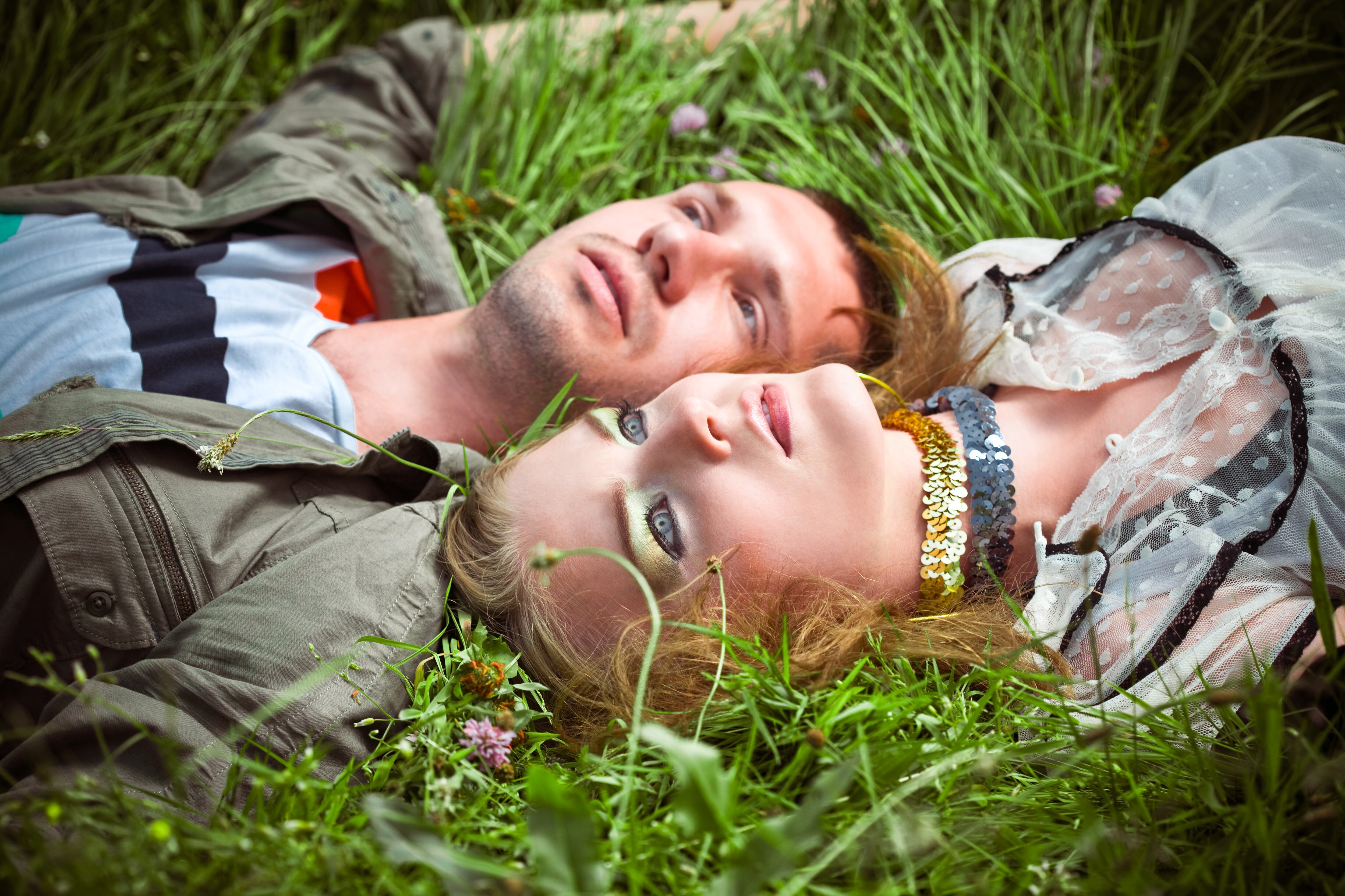 Pareja acostada sobre el pasto, mirando hacia el cielo meditabunda (Crédito: Getty Images)