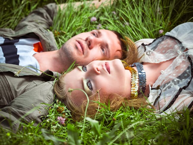 Pareja acostada sobre el pasto, mirando hacia el cielo meditabunda (Crédito: Getty Images)