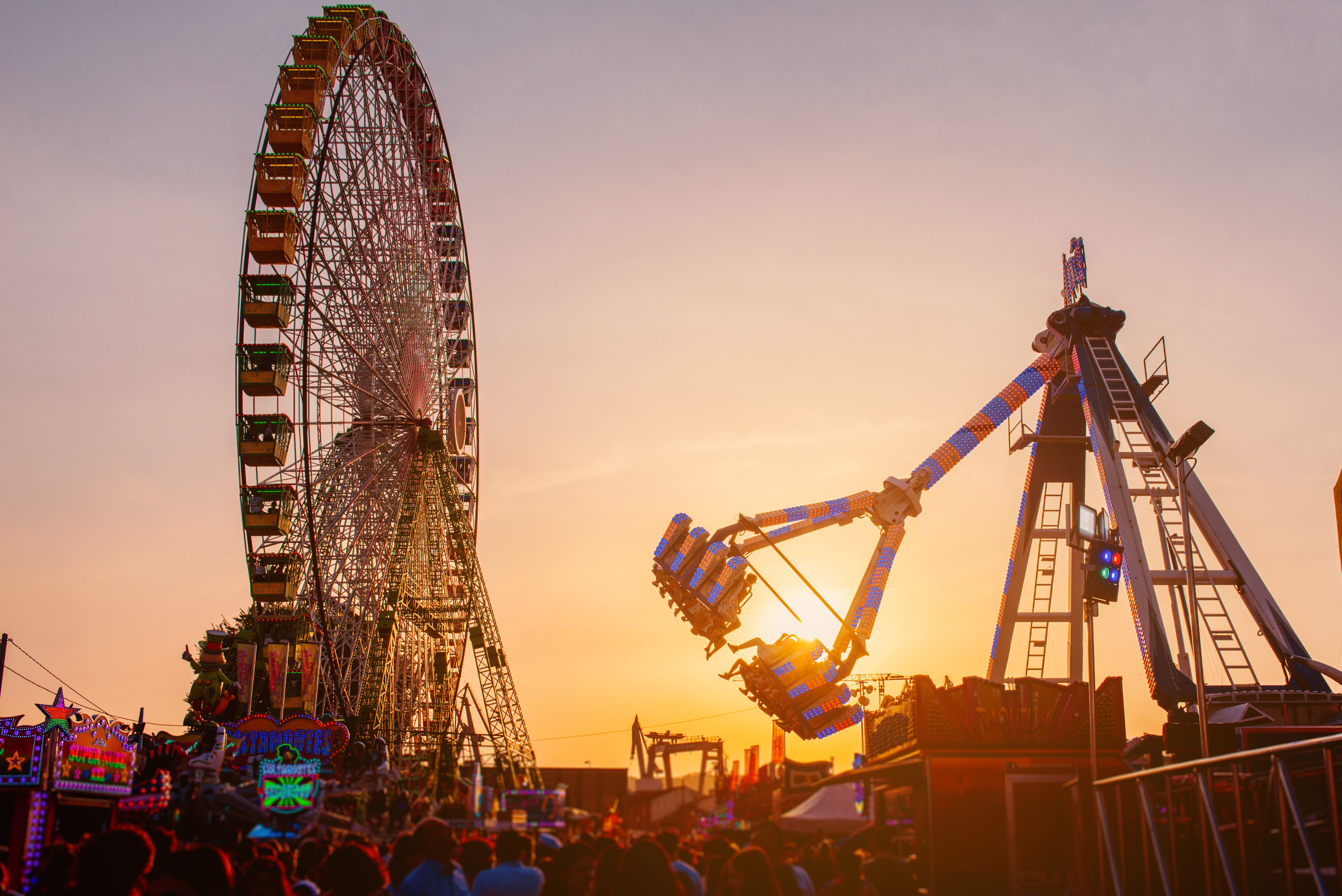ferris wheel and attraction in amusement park at sunset