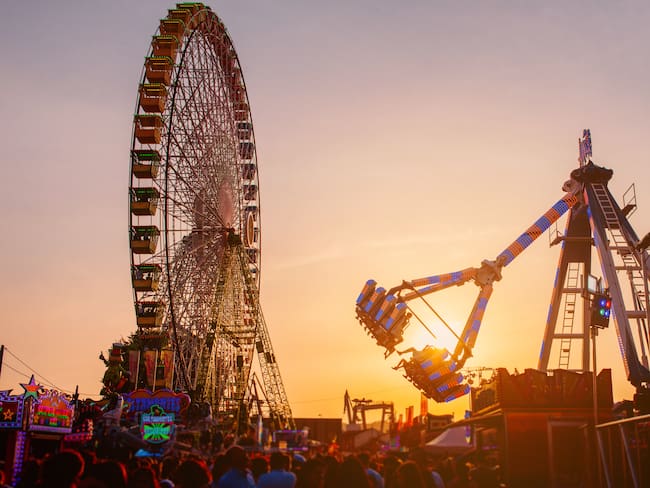 ferris wheel and attraction in amusement park at sunset