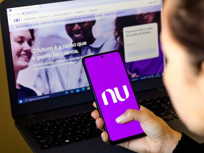 BRAZIL - 2022/04/18: In this photo illustration, a woman holds a smartphone with the Nubank logo displayed on the screen with the Nubank website displayed in the background. (Photo Illustration by Rafael Henrique/SOPA Images/LightRocket via Getty Images)