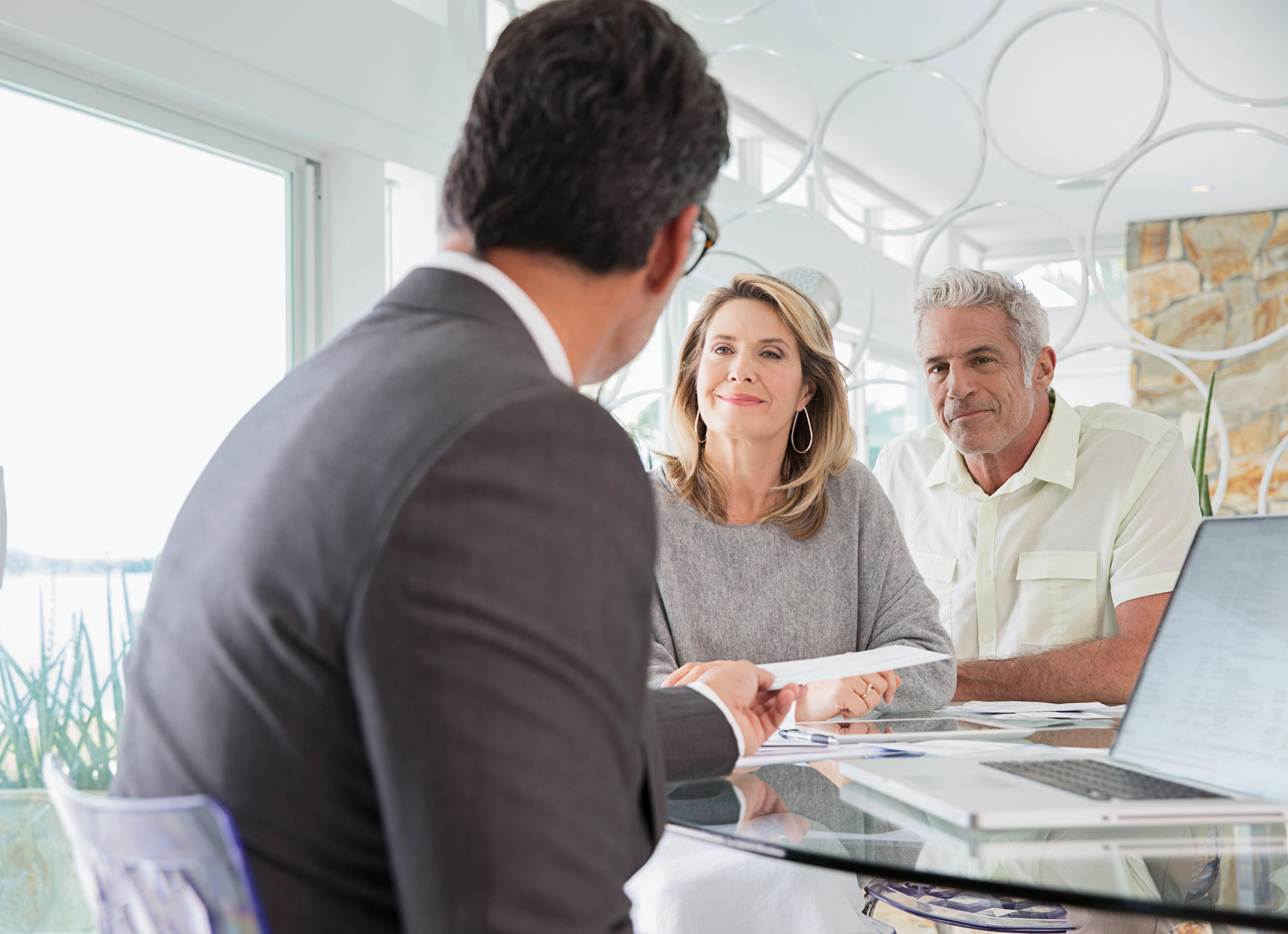 Asesor entregando un documento a dos adultos mayores (Foto vía Getty Images)