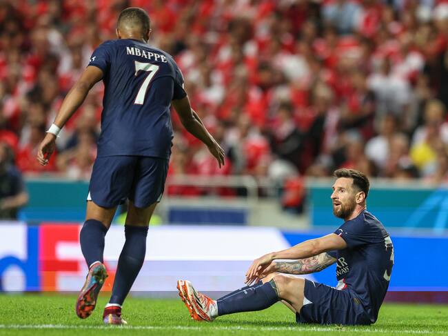 LISBON, PORTUGAL - OCTOBER 05: Kylian Mbappe (L) helps Lionel Messi (R) of Paris Saint-Germain to get up during the UEFA Champions League group H match between SL Benfica and Paris Saint-Germain at Estadio do Sport Lisboa e Benfica on October 5, 2022 in Lisbon, Portugal. (Photo by Carlos Rodrigues/Getty Images)