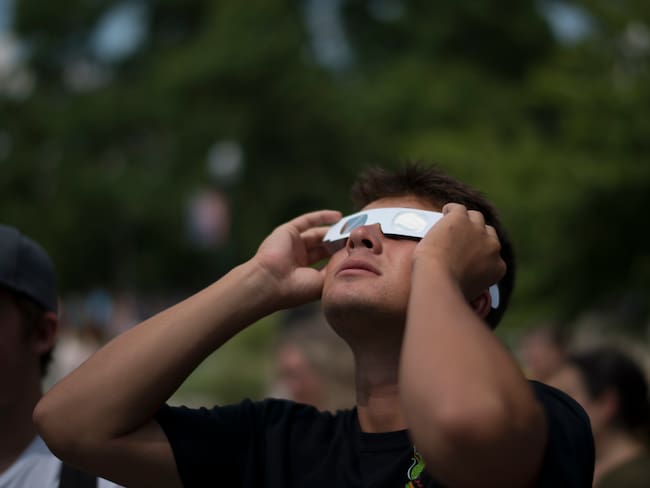 Hombre joven viendo el eclipse solar con gafas de protección (Getty Images)
