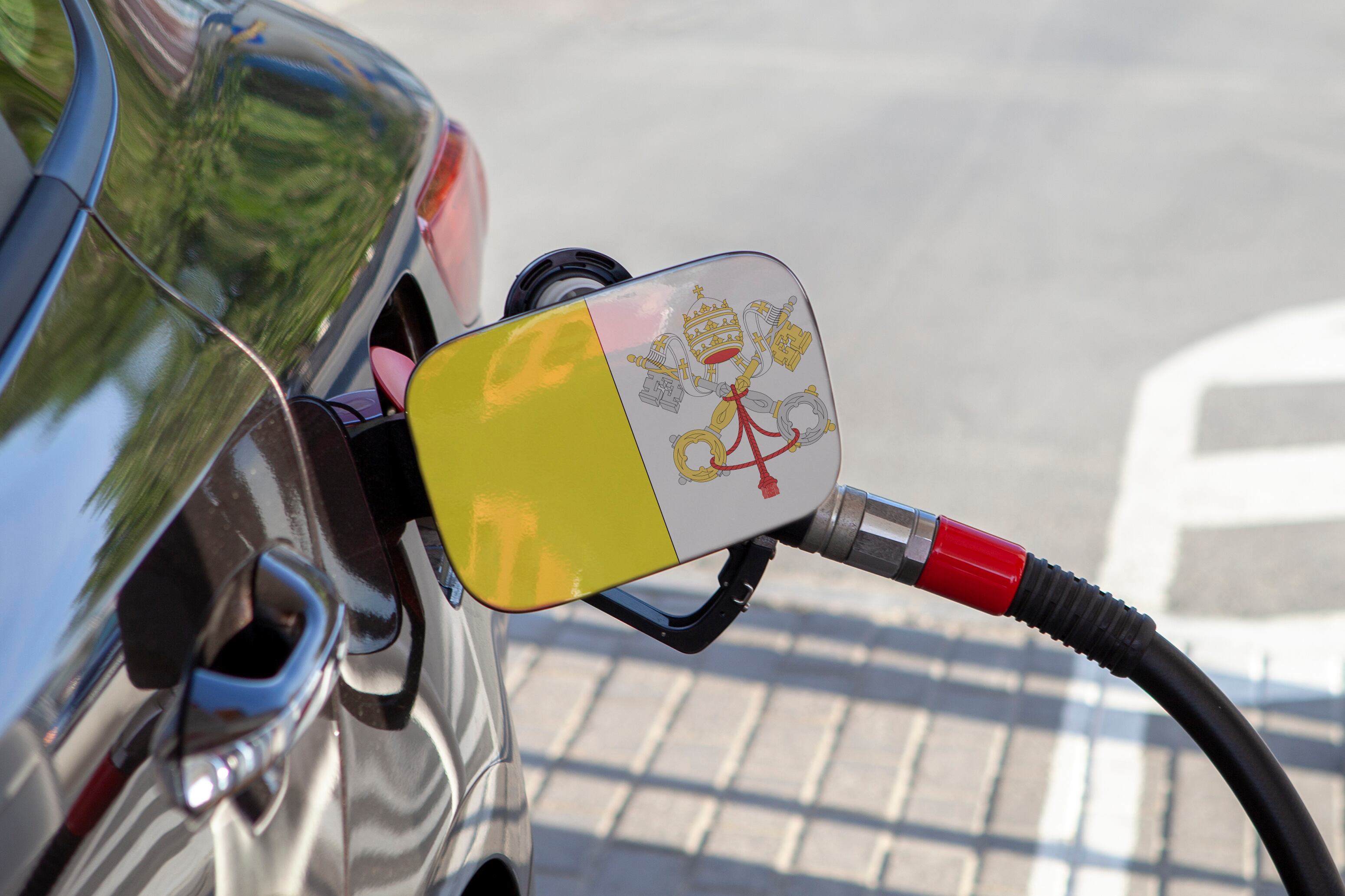 Flag of Vatican on the car's fuel tank filler flap. Fueling car with petrol pump at a gas station. Petrol station. Gasoline and oil products. Close up.