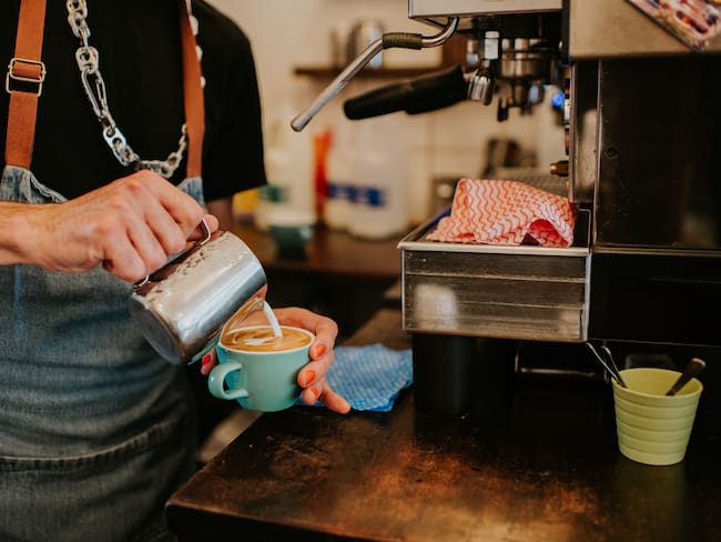 A close-up of a barista making a delicious latte coffee with milk.