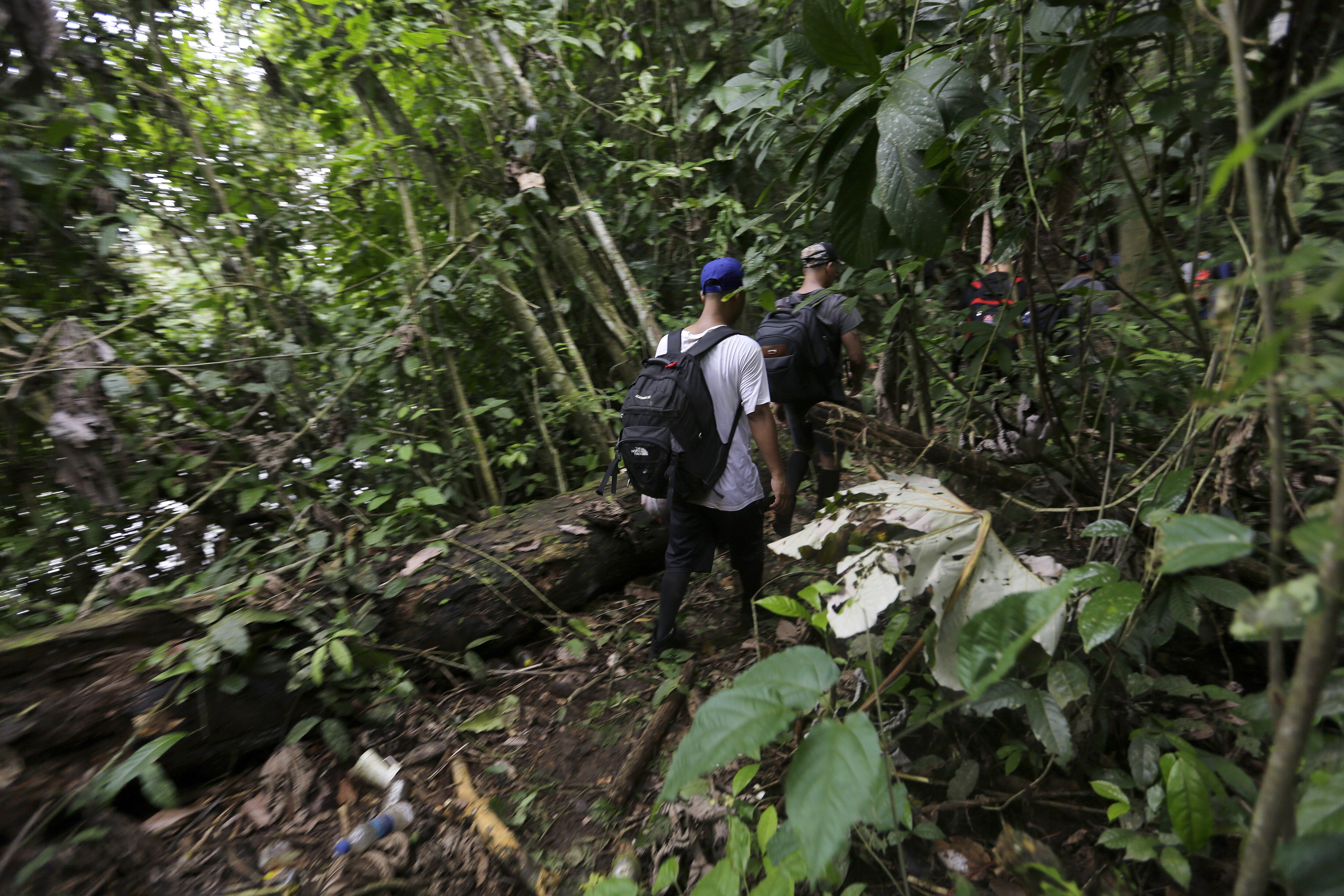 AME4730. DARIÉN (PANAMÁ), 31/08/2024.- Migrantes de diferentes nacionalidades cruzan un campamento en medio de un operativo este sábado en plena selva del Darién, frontera natural entre Colombia y Panamá. Unidades del Servicio Nacional de Fronteras panameño dieron este sábado con un campamento en plena selva de Darién, frontera natural entre Colombia y Panamá, en el que se vendían "ilegalmente" víveres y servicios a migrantes irregulares que cruzan esa peligrosa jungla en su viaje hacia Norteamérica. EFE/Carlos Lemos