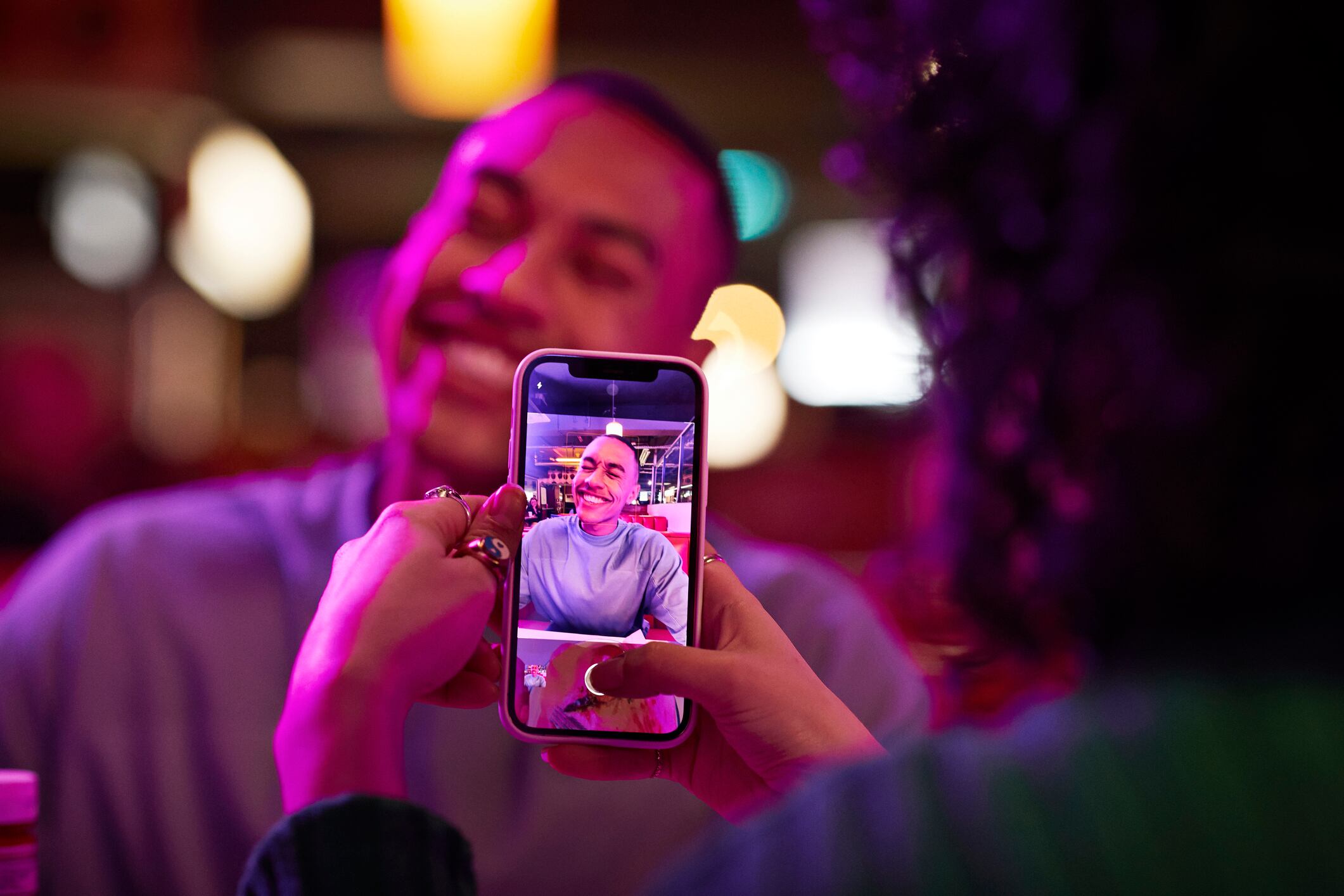 Mujer tomándole foto a su pareja sonriendo con el celular (Getty Images)
