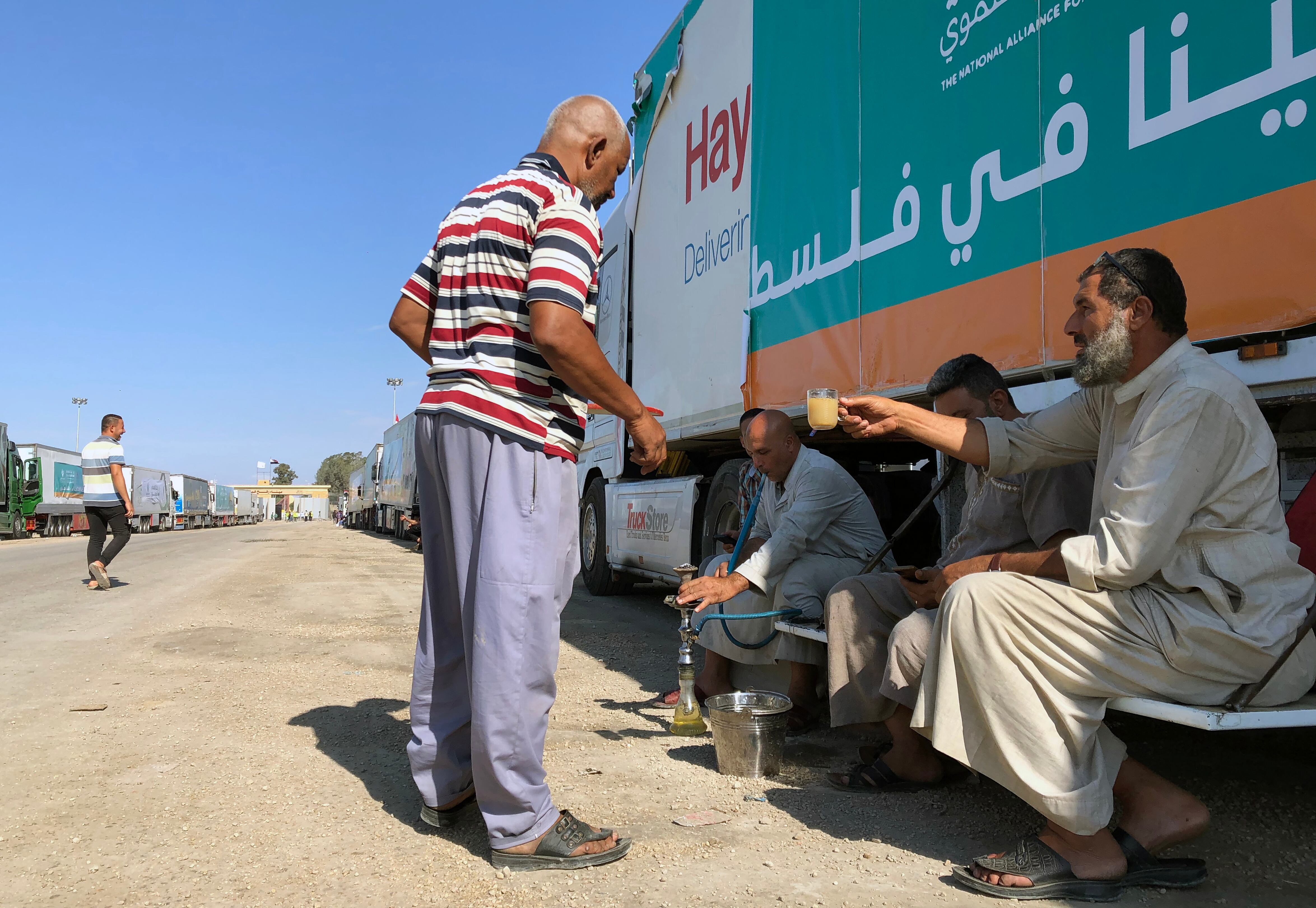 Rafah (Egypt), 17/10/2023.- People rest near a parked truck, which is part of a humanitarian aid convoy for the Gaza Strip, outside the Rafah border gate, Egypt, 17 October 2023. As international mediators continue to push for the passage of aid into Gaza and the exit of foreign nationals fleeing the conflict, from it, Egypt's border crossing with the Gaza Strip in Rafah remained closed on 16 October, with the international aid convoys mostly stationed in the town of Arish some 50km away from Rafah. (Egipto) EFE/EPA/STRINGER