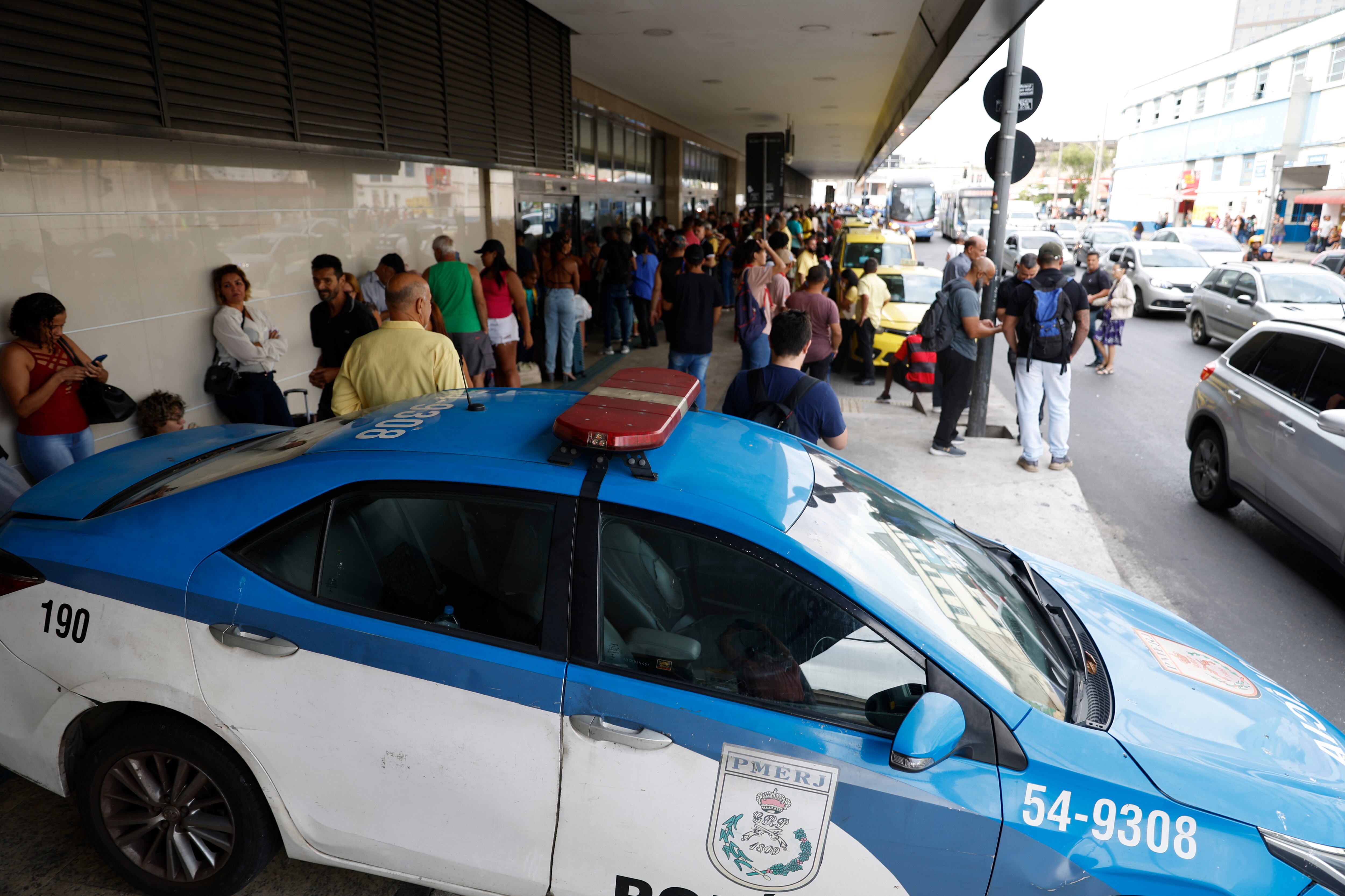 AME8053. RÍO DE JANEIRO (BRASIL), 12/03/2024.- Fotografía de personas y policías a la entrada de la principal terminal de Río de Janeiro Rodoviária do Río donde un hombre armado tomó como rehenes a 17 pasajeros en un autobús estacionado, luego de dejar heridas a tiros a otras dos personas, este martes en Río de Janeiro (Brasil). "Puedo informar que el hecho está superado, que el hombre que tomó los rehenes se entregó y está detenido, y que todos los rehenes fueron liberados", afirmó el portavoz de la Policía Militarizada de Río, coronel Marco Andrade, en declaraciones a la prensa. Pese a que inicialmente las autoridades habían indicado que los pasajeros fueron tomados rehenes tras un asalto frustrado al autobús, Andrade aclaró que esa información no ha sido confirmada hasta ahora. EFE/ Antonio Lacerda