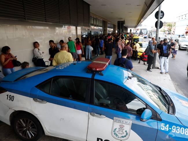 AME8053. RÍO DE JANEIRO (BRASIL), 12/03/2024.- Fotografía de personas y policías a la entrada de la principal terminal de Río de Janeiro Rodoviária do Río donde un hombre armado tomó como rehenes a 17 pasajeros en un autobús estacionado, luego de dejar heridas a tiros a otras dos personas, este martes en Río de Janeiro (Brasil). "Puedo informar que el hecho está superado, que el hombre que tomó los rehenes se entregó y está detenido, y que todos los rehenes fueron liberados", afirmó el portavoz de la Policía Militarizada de Río, coronel Marco Andrade, en declaraciones a la prensa. Pese a que inicialmente las autoridades habían indicado que los pasajeros fueron tomados rehenes tras un asalto frustrado al autobús, Andrade aclaró que esa información no ha sido confirmada hasta ahora. EFE/ Antonio Lacerda