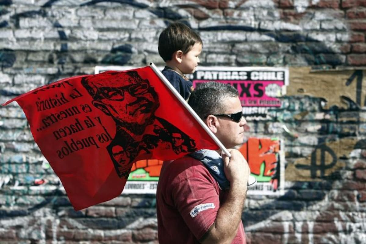 Un hombre y su hijo participan en la marcha, junto a miles de chilenos con banderas y fotografías de desaparecidos
