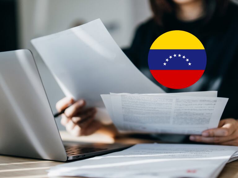 Persona revisando documentos con bandera de Venezuela (Getty Images)