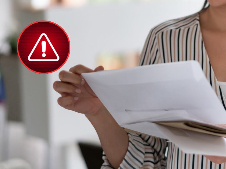 Persona leyendo una carta y al lado una señal de alerta (Fotos vía Getty Images)