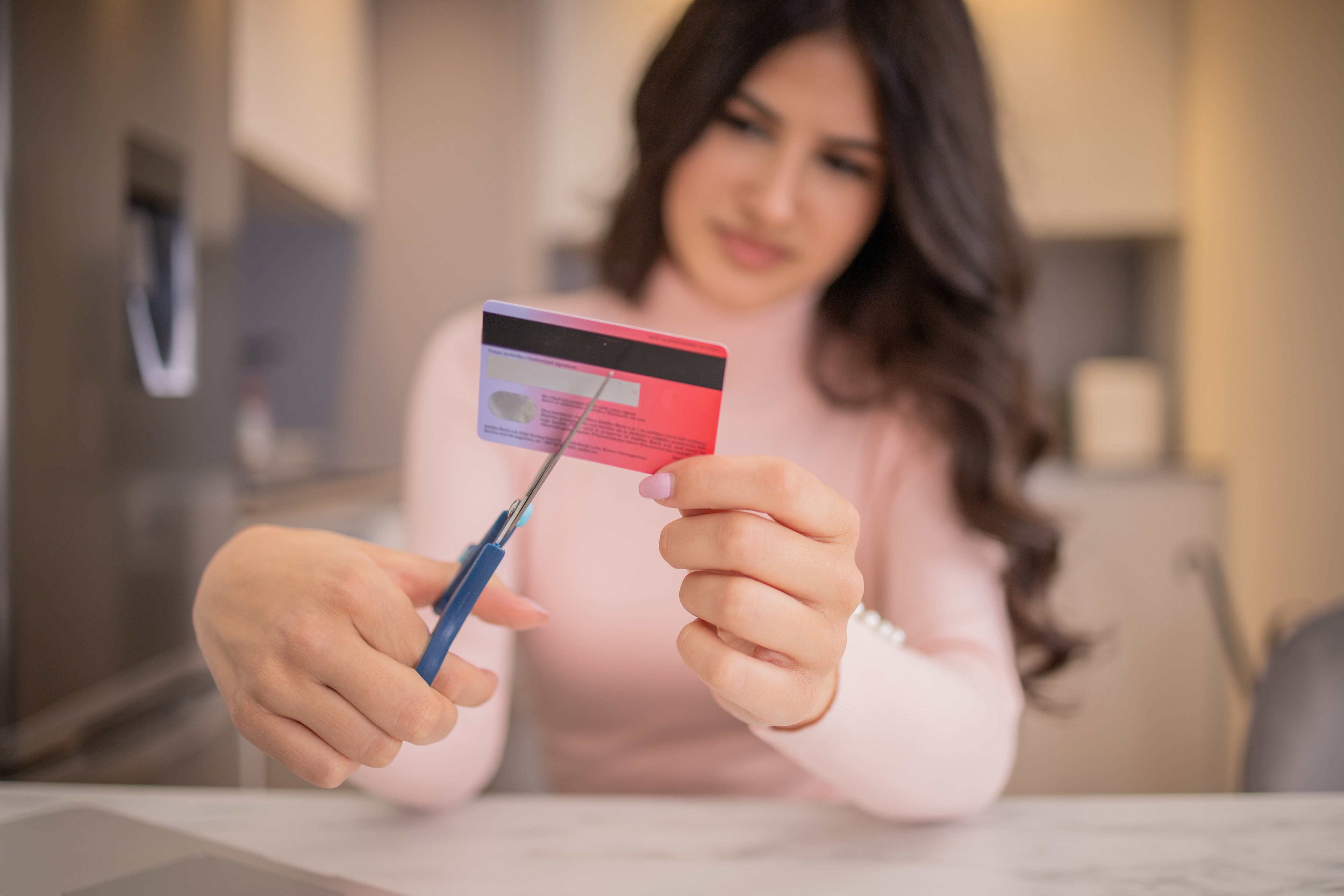 Mujer cortando el flástico de una tarjeta débito. (Foto vía Getty Images)