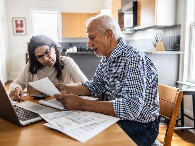 Senior couple paying bills at kitchen table