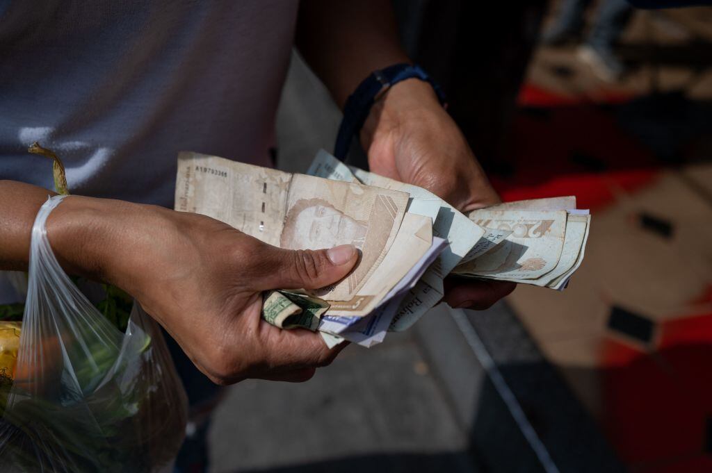 A woman counts Bolivar bills to buy food in the street in Caracas on April 28, 2023. (Photo by Federico PARRA / AFP) (Photo by FEDERICO PARRA/AFP via Getty Images)