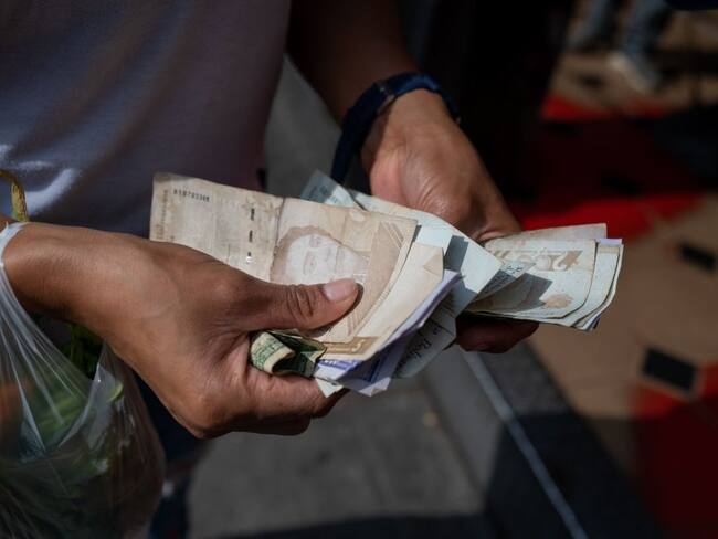 A woman counts Bolivar bills to buy food in the street in Caracas on April 28, 2023. (Photo by Federico PARRA / AFP) (Photo by FEDERICO PARRA/AFP via Getty Images)