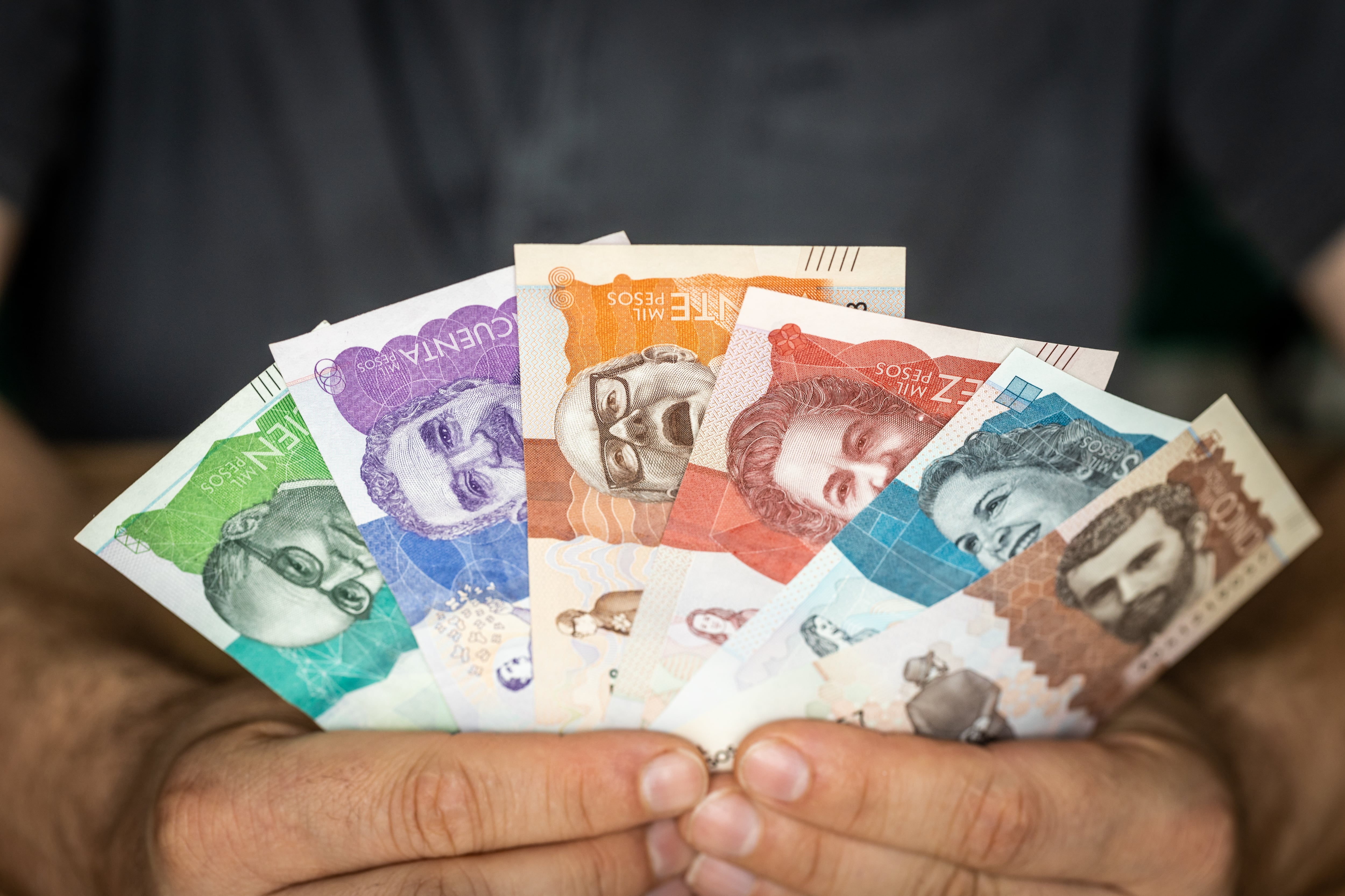 Hombre sosteniendo billetes colombianos de diferentes denominaciones (Getty Images)