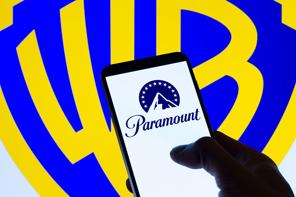 The Paramount logo is displayed on a mobile phone with the Warner Bros. Discovery icon seen in the background, in this photo illustration in Brussels, Belgium, on December 9, 2025. (Photo by Jonathan Raa/NurPhoto via Getty Images)