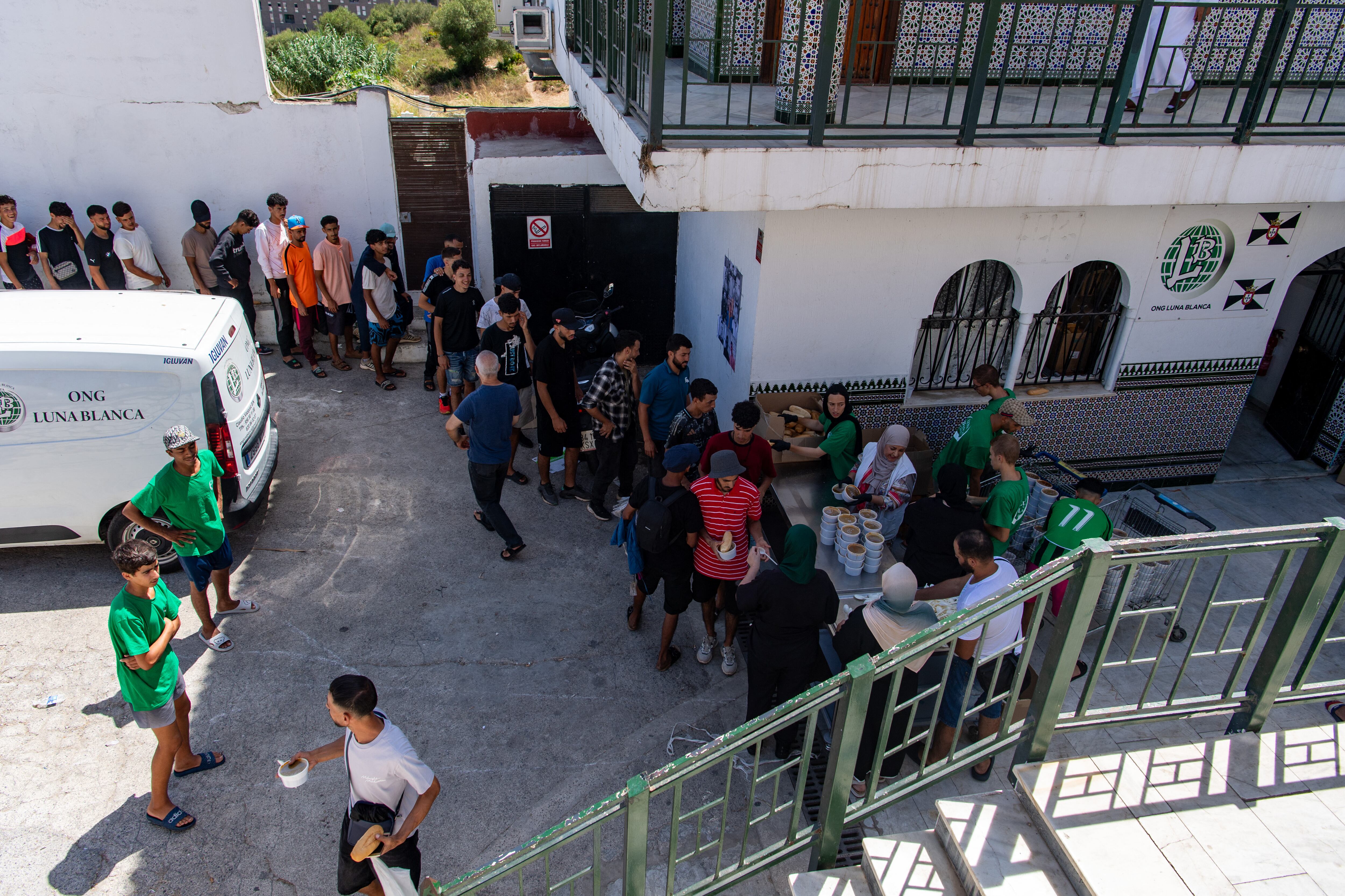 Migrants queue to get food distibuted by NGO Luna Blanca in the Spanish North African enclave of Ceuta on August 7, 2026, following a mass influx of migrants from Morocco in recent days. Of the 72,000 migrants who reached Ceuta, 70,000 have returned to Morocco, according to official Spanish figures, which have recorded 80 deaths. Morocco's interior ministry has said 11 people died on the Moroccan side of the border, all but one by drowning. Those who remain in Ceuta -- including hundreds of unaccompanied children -- face dire living conditions with little access to food, water, shelter and sanitation. (Photo by Antonio Sempere / AFP)
