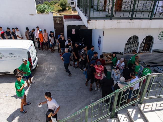 Migrants queue to get food distibuted by NGO Luna Blanca in the Spanish North African enclave of Ceuta on August 7, 2026, following a mass influx of migrants from Morocco in recent days. Of the 72,000 migrants who reached Ceuta, 70,000 have returned to Morocco, according to official Spanish figures, which have recorded 80 deaths. Morocco's interior ministry has said 11 people died on the Moroccan side of the border, all but one by drowning. Those who remain in Ceuta -- including hundreds of unaccompanied children -- face dire living conditions with little access to food, water, shelter and sanitation. (Photo by Antonio Sempere / AFP)