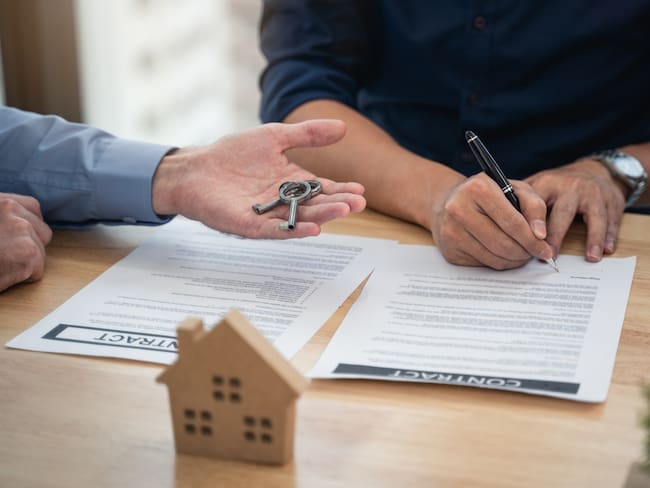 Dos personas firmando un contrato y entregando las llaves de la vivienda (Getty Images)