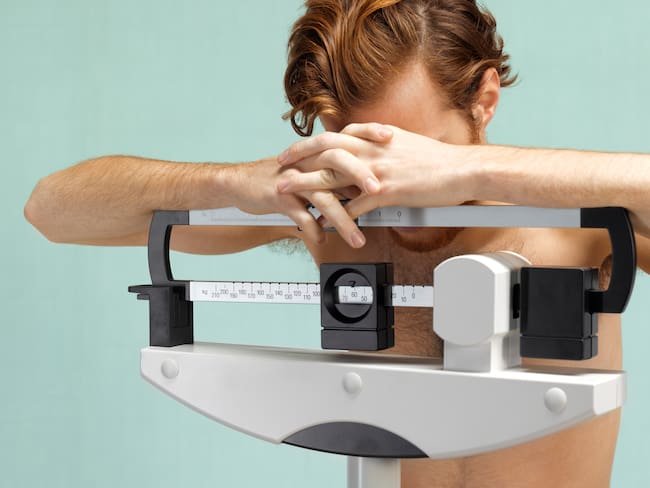 Hombre frustrado sobre una báscula de peso corporal (Getty Images)