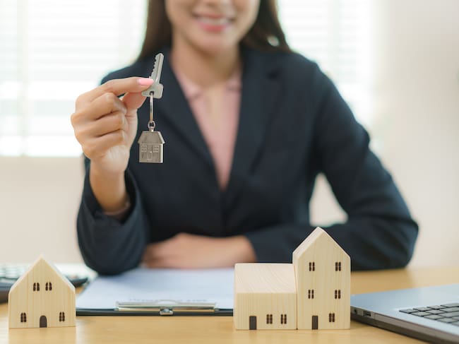 Real estate agent with house model and holding keys, customer signing contract to buy house, insurance or loan real estate.