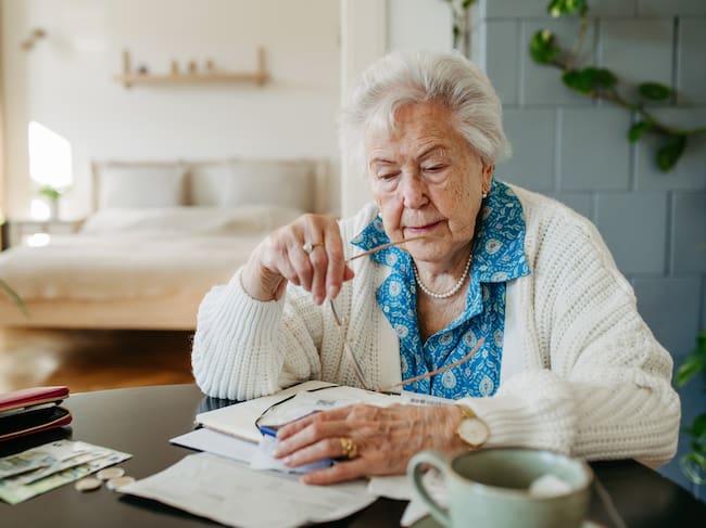 Senior woman has financial problems. Counting money, monthly pension, don’t have enough money for paying bills.