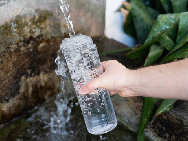 Persona sirviendo agua en una botella de agua (Getty Images)