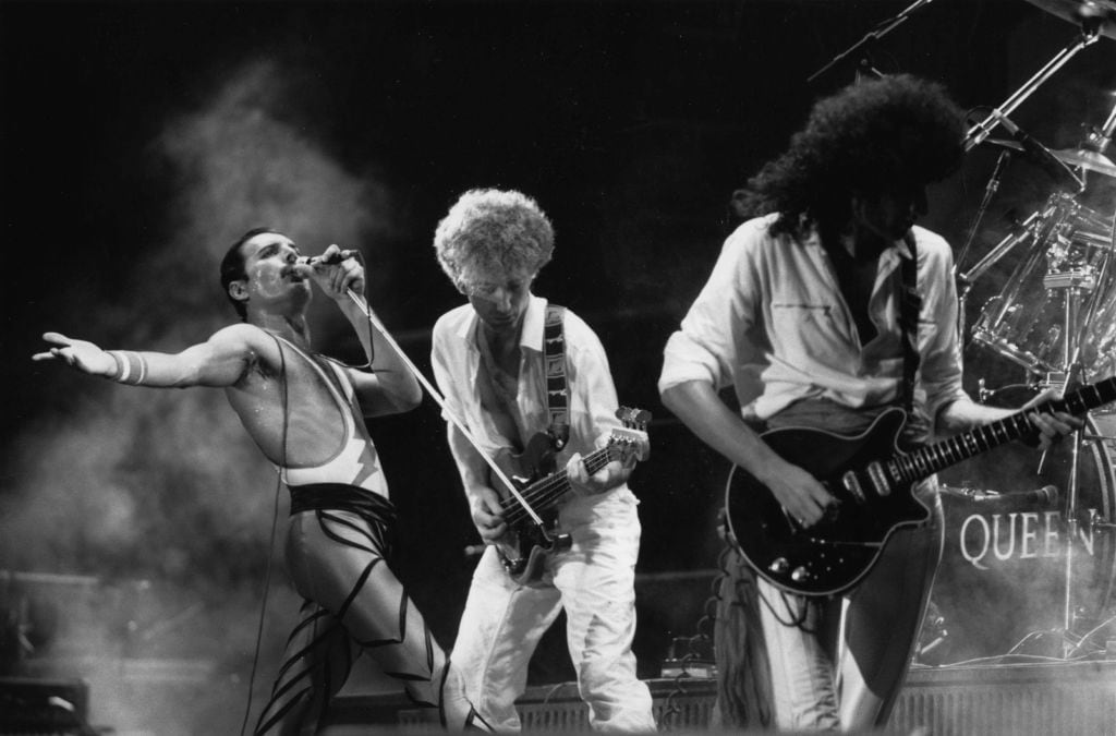 British rock group Queen in concert, from left to right; Freddie Mercury (Frederick Bulsara, 1946 - 1991), John Deacon, and Brian May. Original Publication: People Disc - HU0463 (Photo by Express Newspapers/Getty Images)
