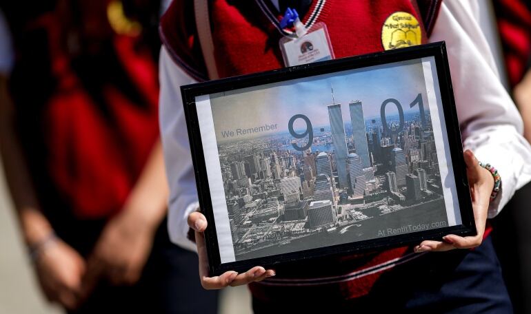 Estudiantes  sostienen fotografías de las Torres Gemelas de Nueva York durante una marcha con motivo del 17 aniversario de los atentados de 2001 