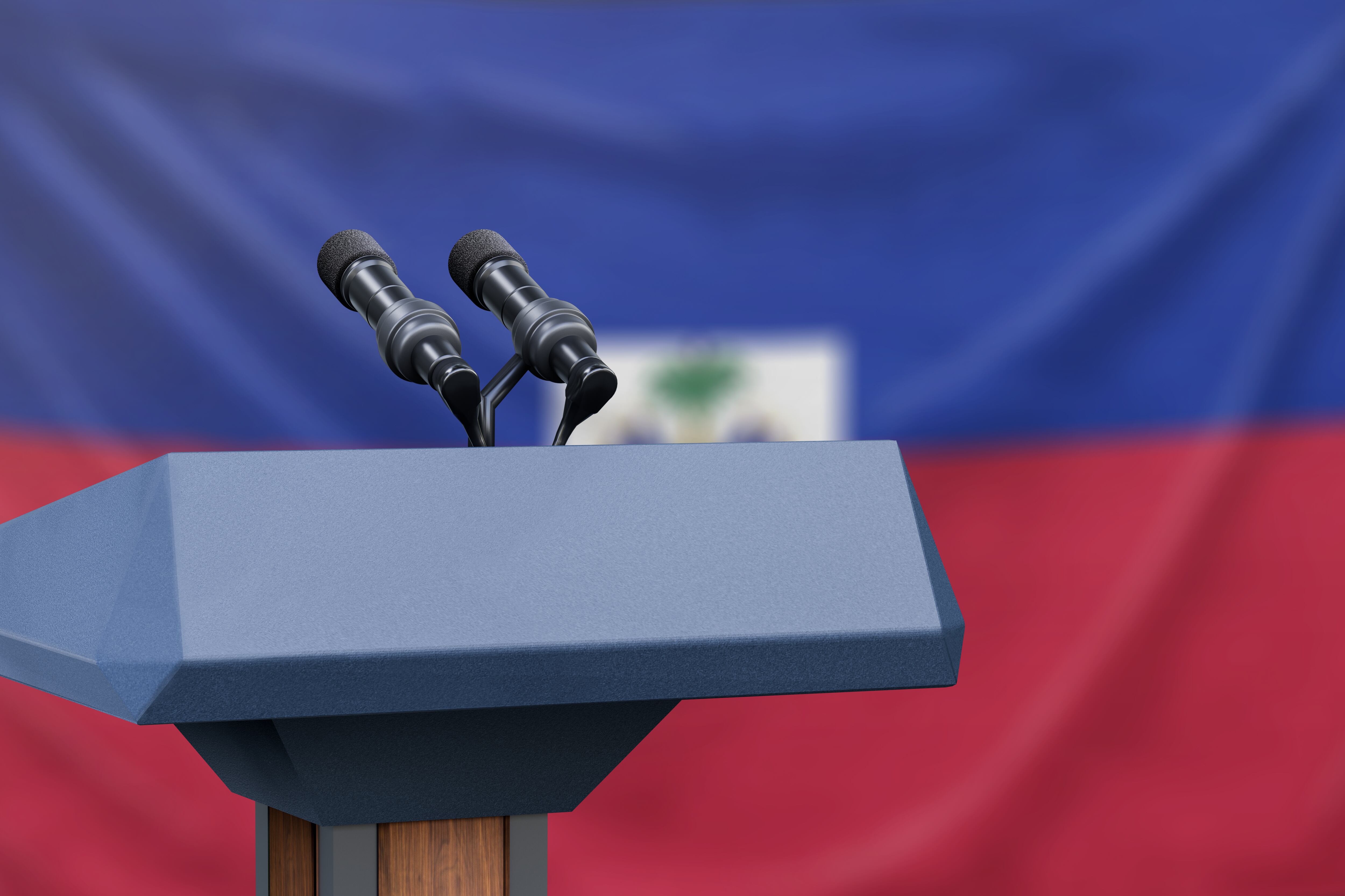 Podium lectern with two microphones and Haiti flag in background