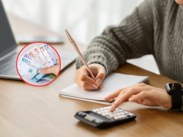 Persona haciendo cuentas con una calculadora y de fondo billetes colombianos de diferente denominación (Fotos vía Getty Images)