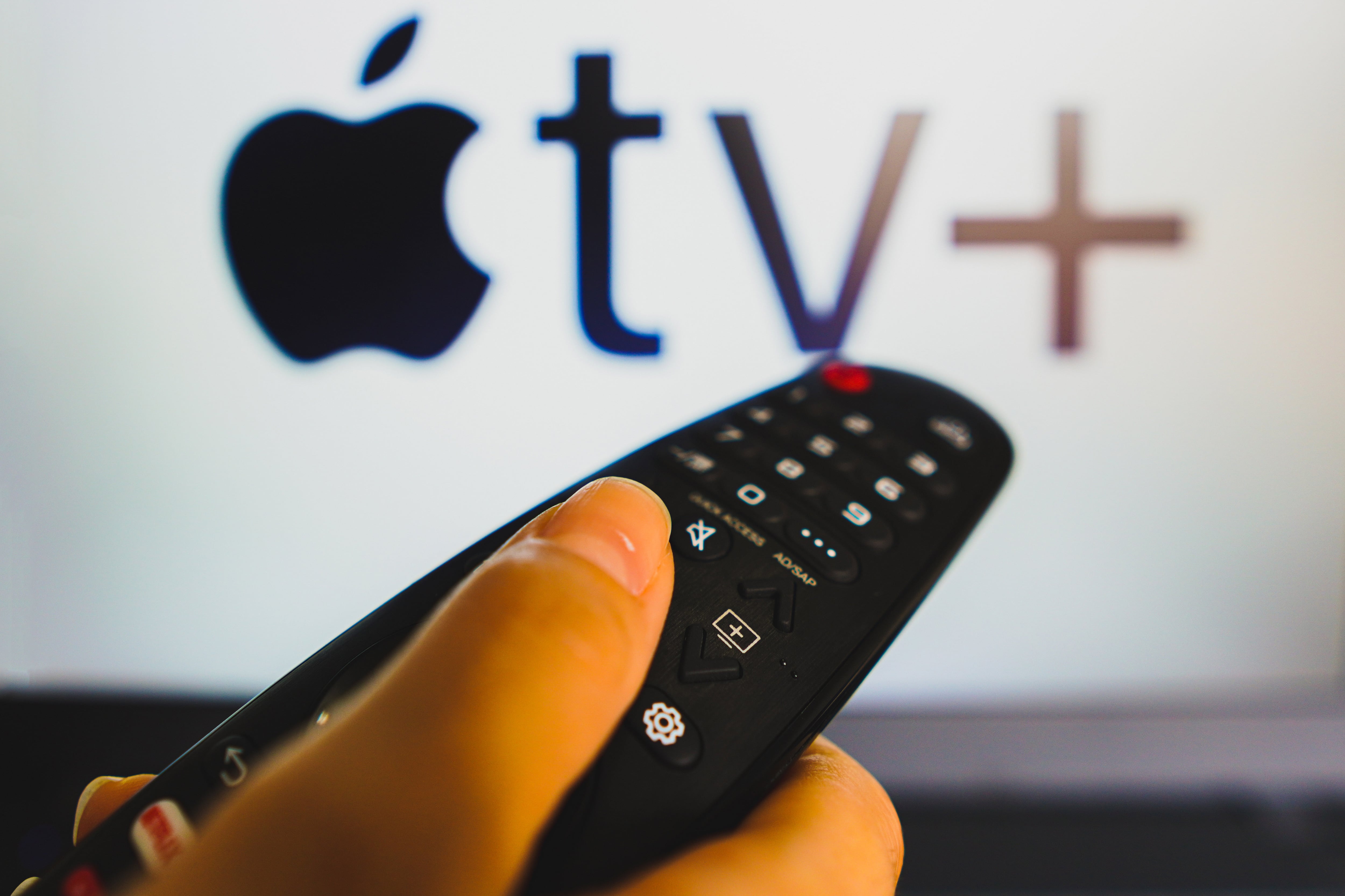 In this photo illustration, a hand holding a TV remote control in front of the Apple TV+ (Plus) logo on a TV screen. (Photo Illustration by Rafael Henrique/SOPA Images/LightRocket via Getty Images)