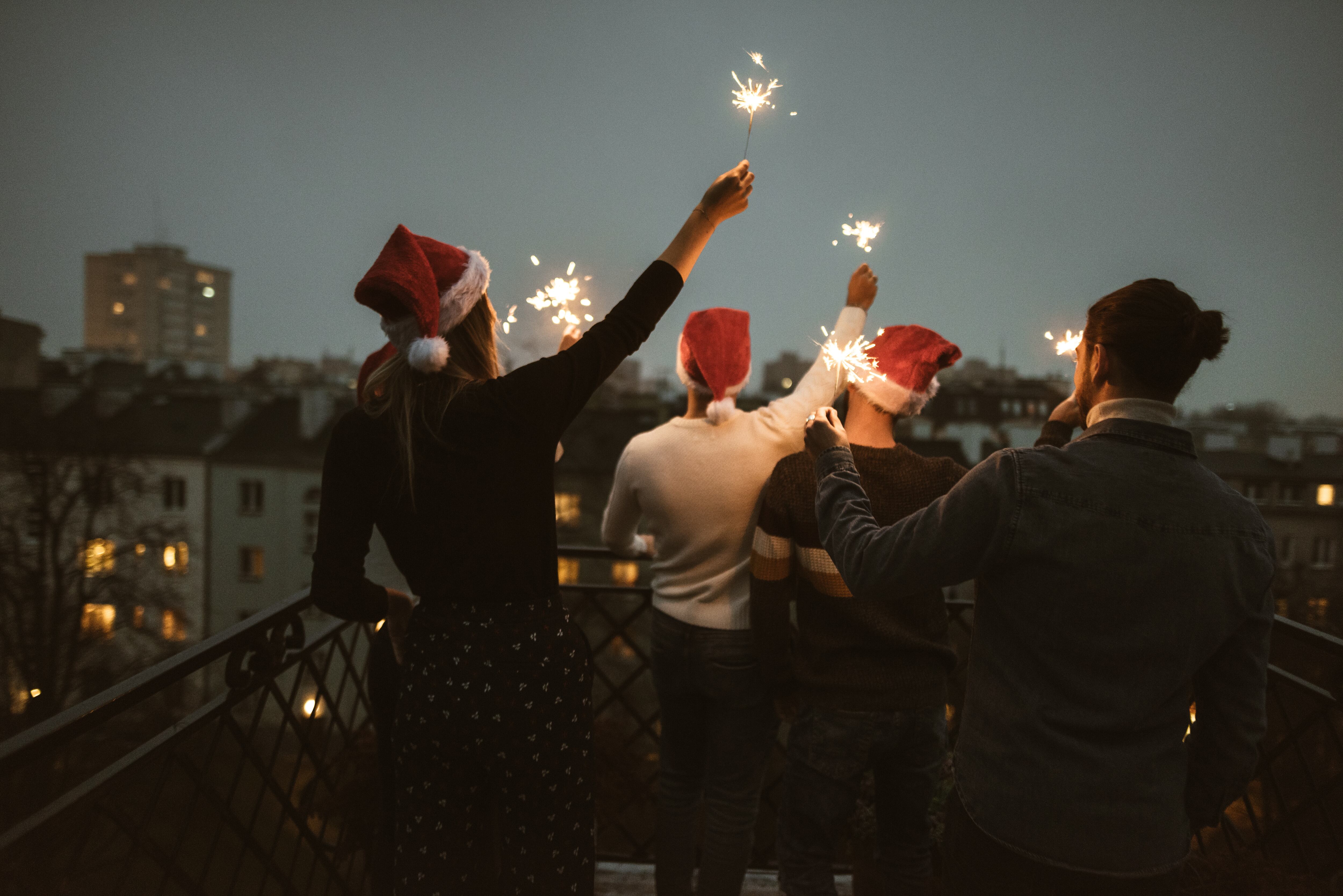Amigos celebran la Navidad en una azotea con gorros navideños (Foto vía Getty Images)