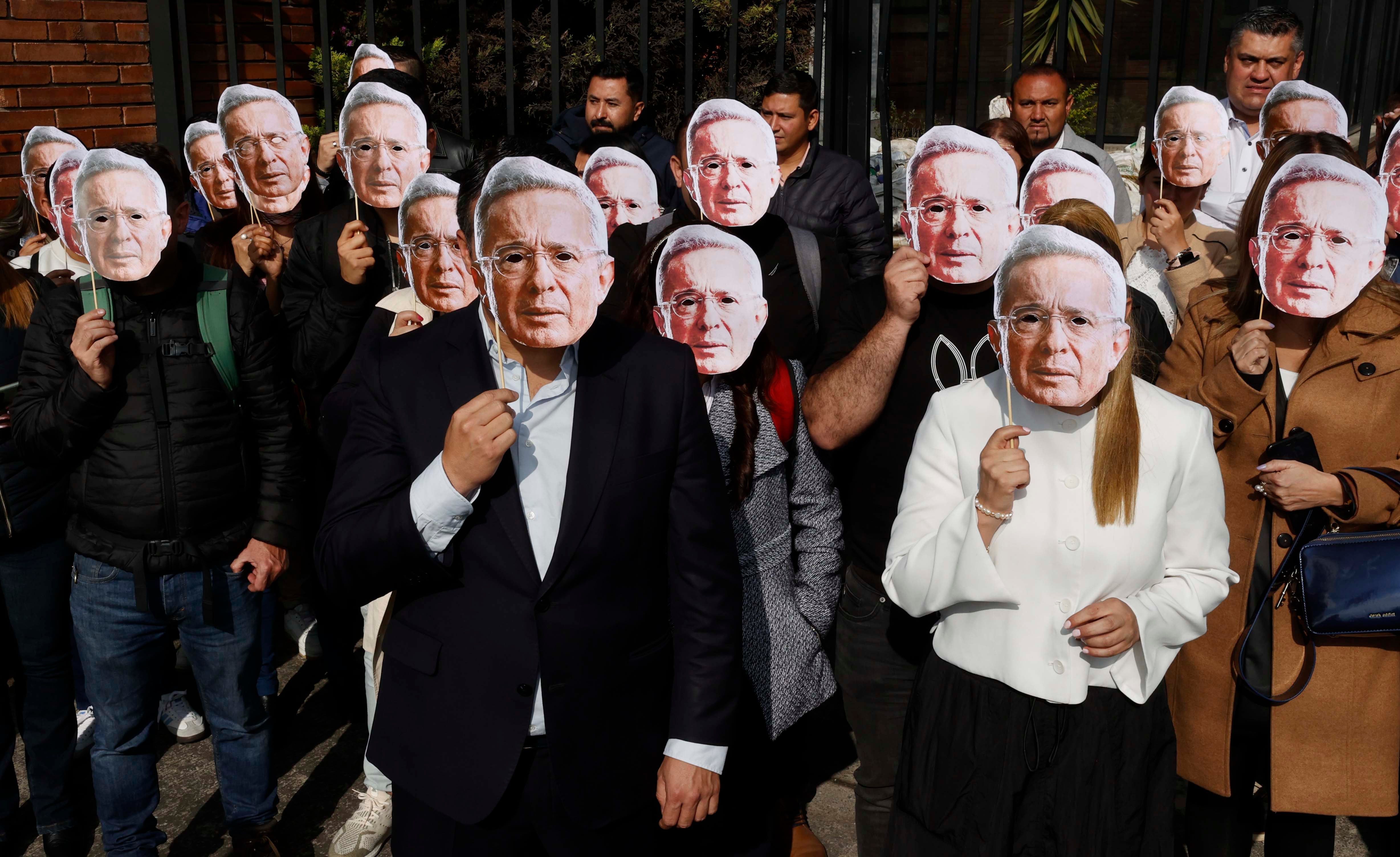 AME8896. BOGOTÁ (COLOMBIA), 10/02/2025.- Personas usan mascaras con la imagen del expresidente colombiano Álvaro Uribe este lunes, en el complejo judicial de Paloquemao en Bogotá (Colombia). Las víctimas del caso judicial contra Uribe solicitaron este lunes a la Comisión Interamericana de Derechos Humanos (CIDH), a la ONU y a otras organizaciones que envíen observadores internacionales para el juicio contra el exmandatario. EFE/ Mauricio Dueñas Castañeda