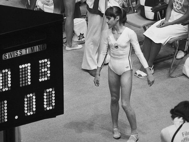 Nadia Comăneci mira el marcador olímpico, que muestra su puntuación perfecta de 10,0 como 1,00, ya que el computador y el sistema de visualización no estaban preparados para manejar lo que Nadia iba a lograr en la competencia olímpica de gimnasia. Ella ha realizado la exhibición más asombrosamente perfecta de gimnasia general jamás vista en los Juegos Olímpicos. Getty Images
