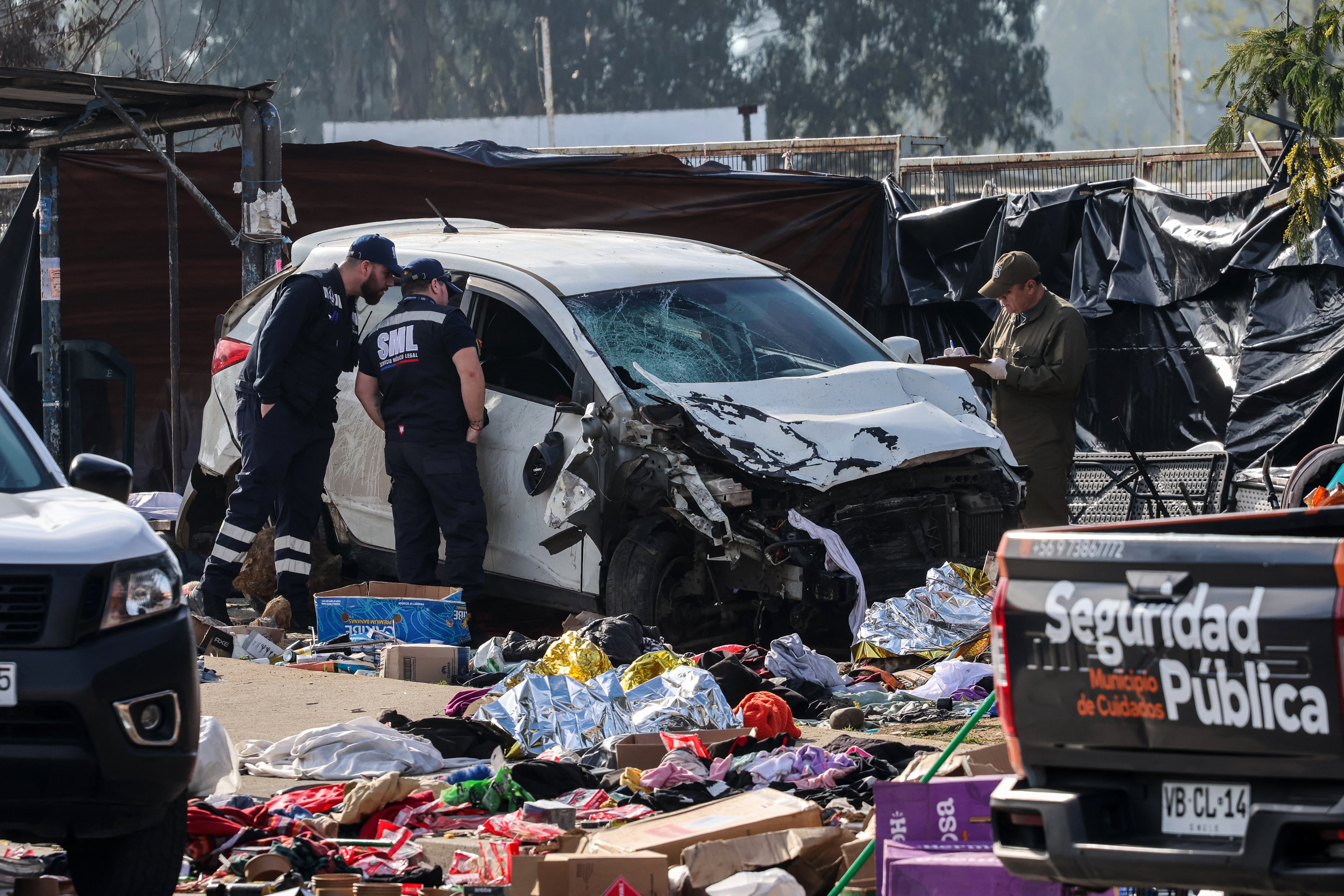 Members of the Carabineros work next to a vehicle that struck several people at a street market in Vina del Mar, Chile, on July 12, 2026. At least six people were killed and seven others were injured on July 12 after being struck by a vehicle at a street market in Vina del Mar, Chilean police said. (Photo by Cristobal BASAURE / AFP)